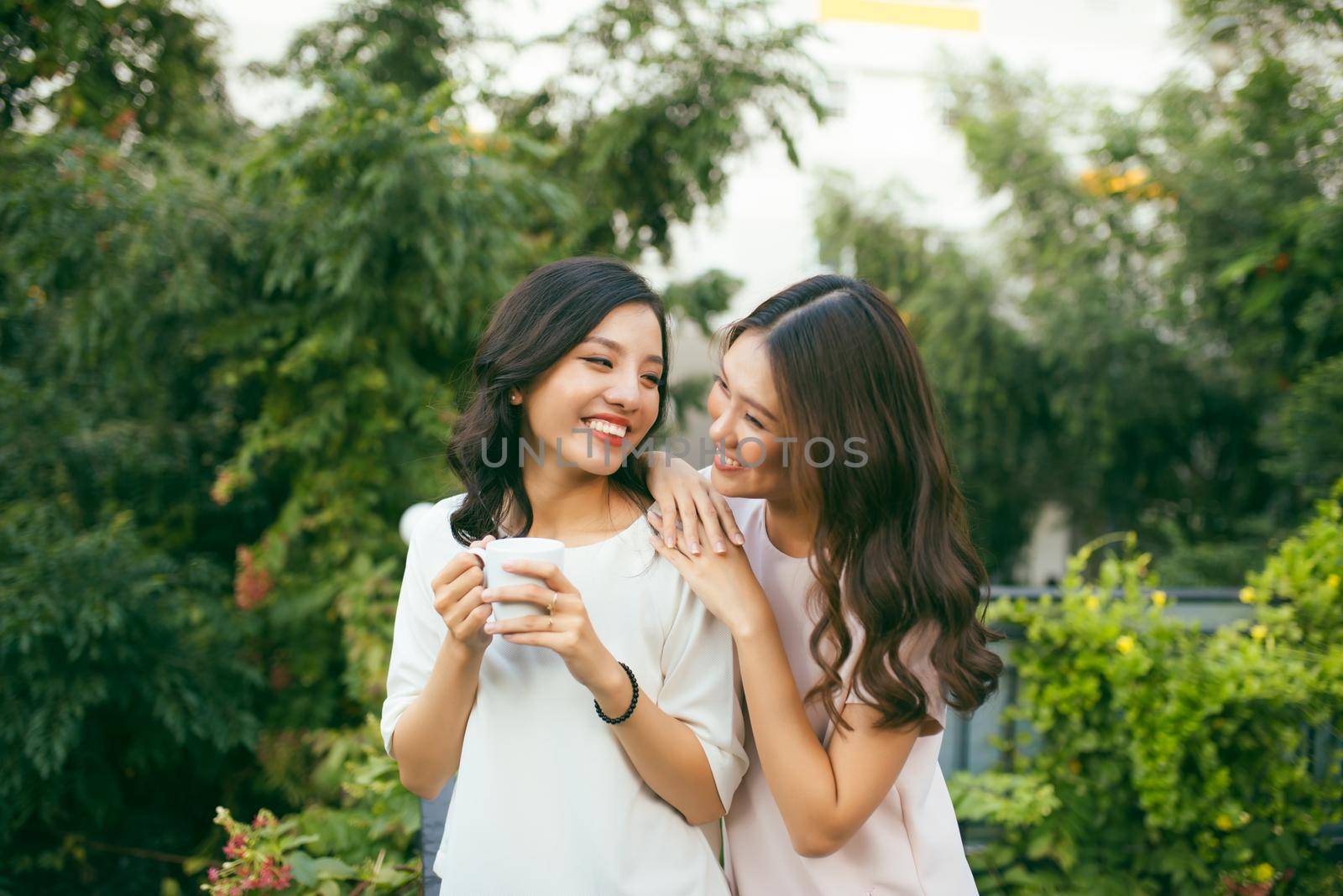 Two Women Relaxing On Rooftop Garden Drinking Coffee