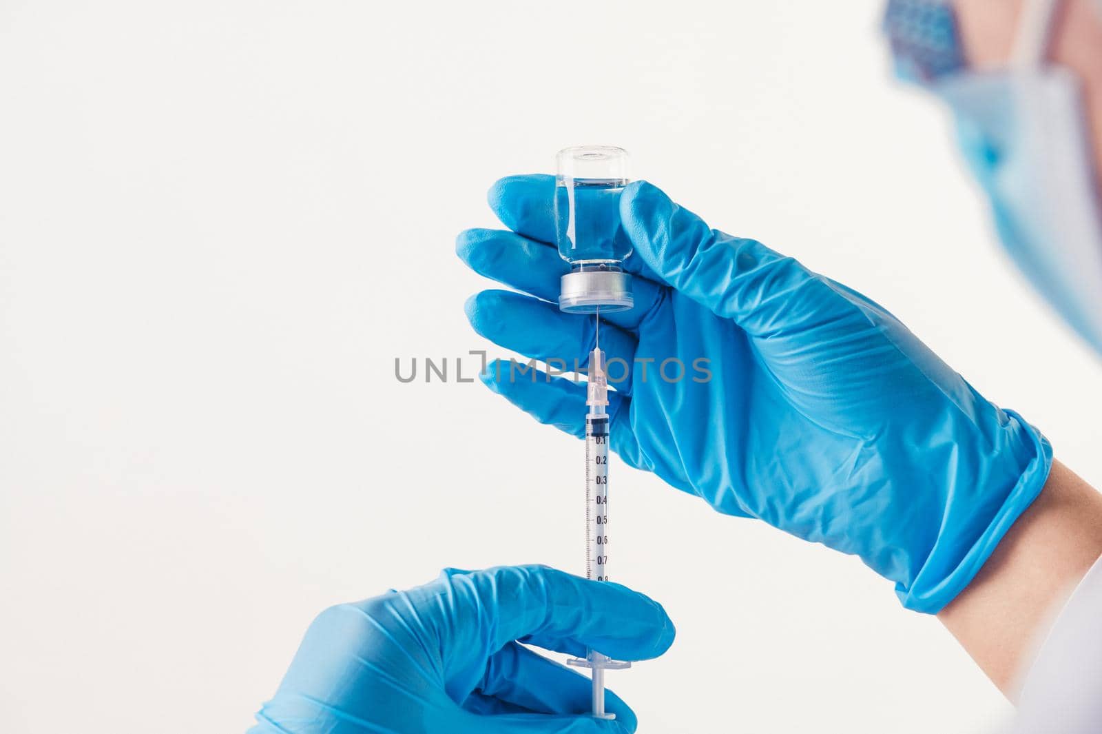 Closeup vial and needle of covid-19 vaccine in hand of scientist doctor in laboratory for treatment with mask gloves and lab coat on white background. Health business and industry concept. Copy space