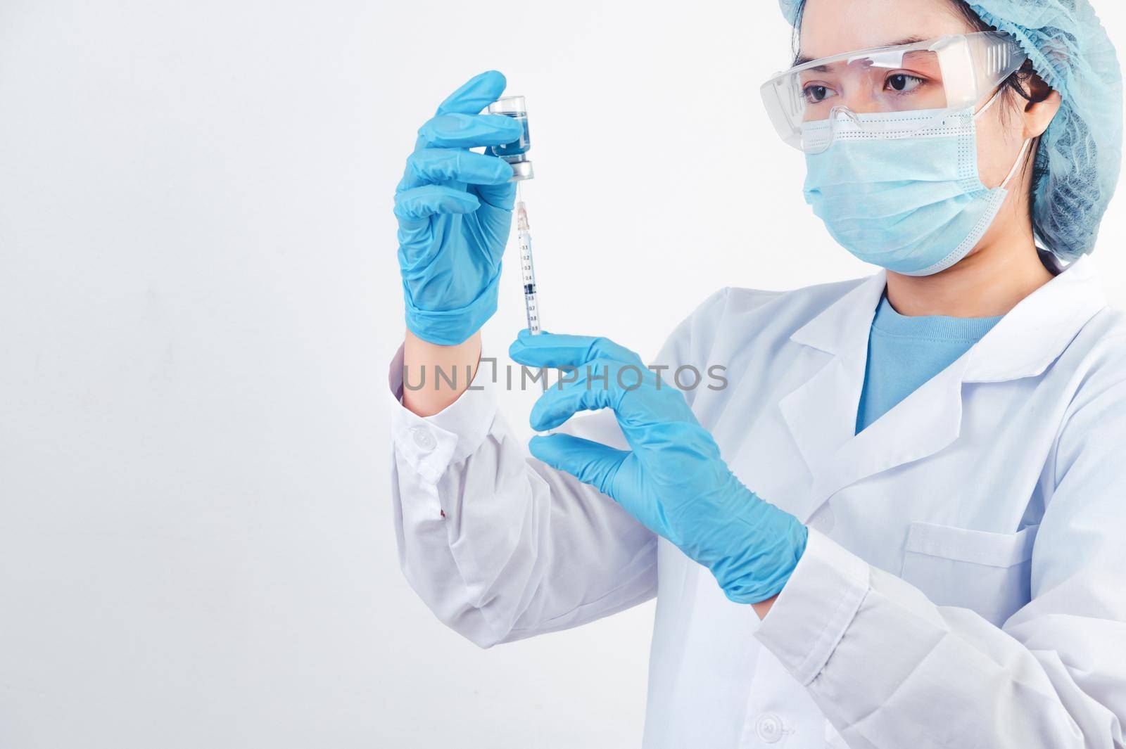 Asian doctor looking and preparing syringe vaccine and vial for injection to illness patient on white background. Medical people and illness prevention technology concept. Coronavirus epidemic theme