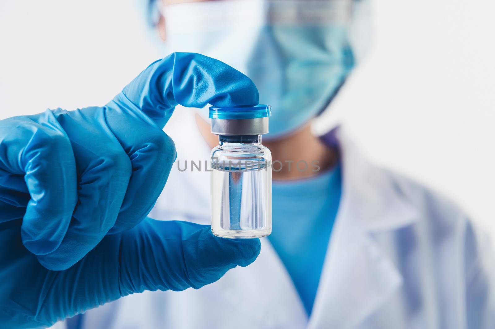 Closeup vial of covid-19 vaccine in hand of professional scientist or doctor in laboratory for treatment with mask gloves and lab coat on white background. Health business and industry concept.