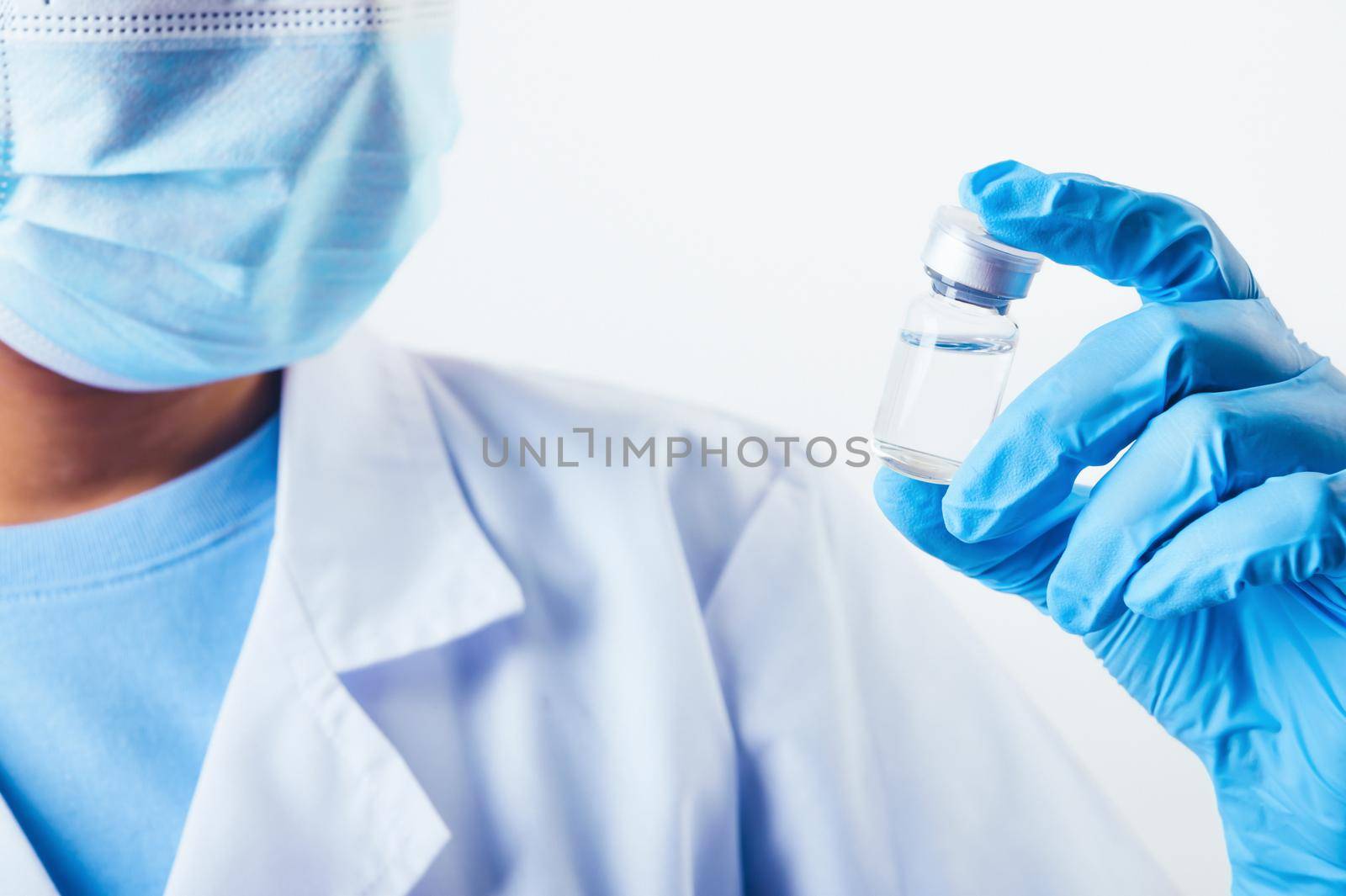 Closeup vial of covid-19 vaccine in hand of professional scientist or doctor in laboratory for treatment with mask gloves and lab coat on white background. Health business and industry concept.