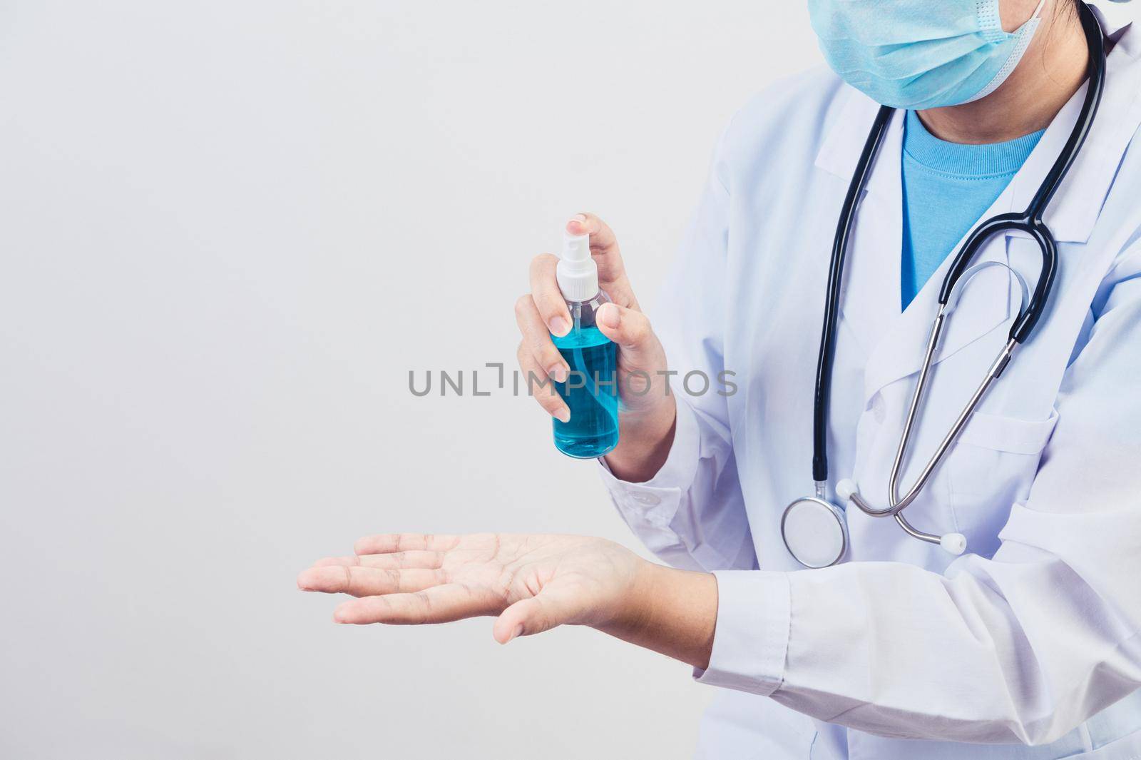 Doctor sprays hand sanitizer or gel dispenser to clean hands and kill viruses and bacteria to patients as example. Medical health people and illness protective concept. 