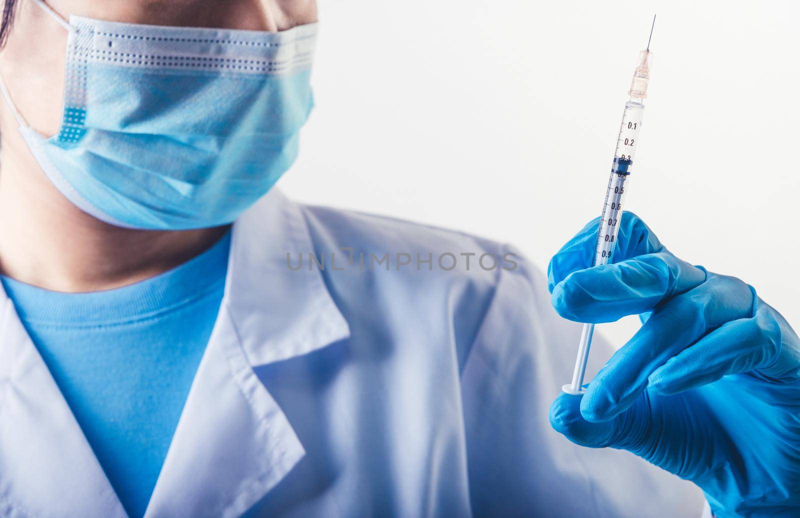Closeup needle of covid-19 vaccine in hand of professional scientist or doctor in laboratory for treatment with mask gloves and lab coat on white background. Health business and industry concept. by MiniStocker