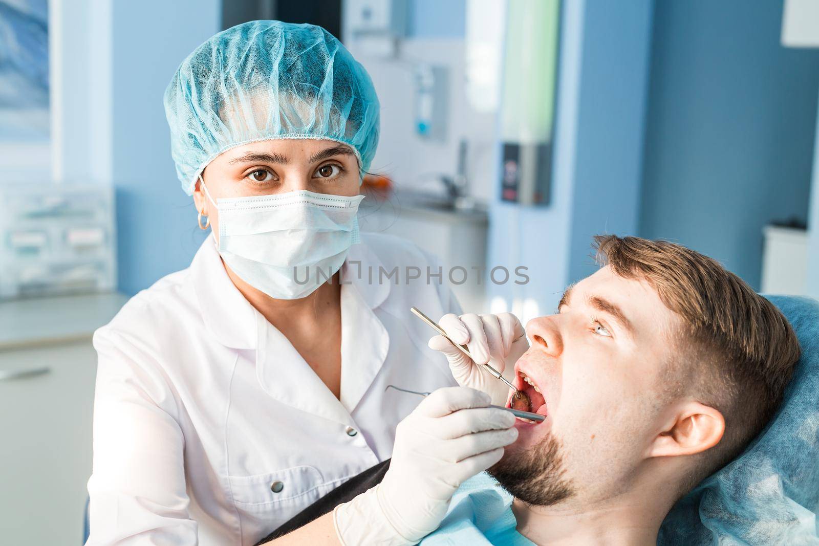 Woman dentist working at her patients teeth.