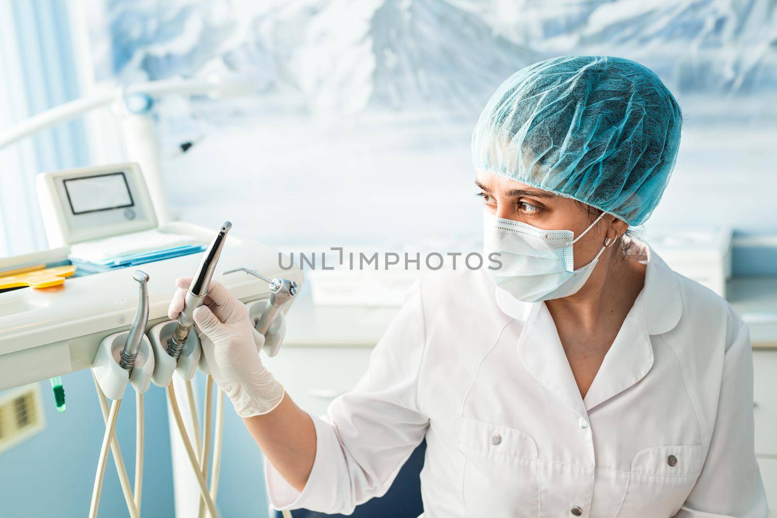 people, medicine, stomatology and healthcare concept - happy young female dentist with tools over medical office background.