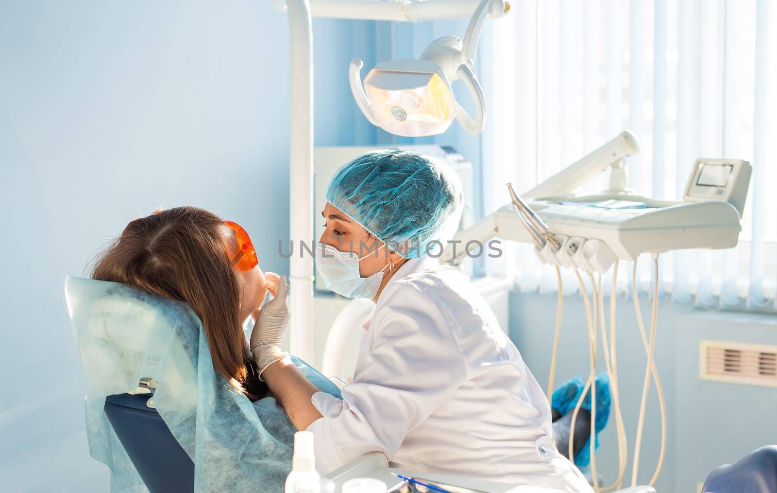 Young woman dentist at work with patient