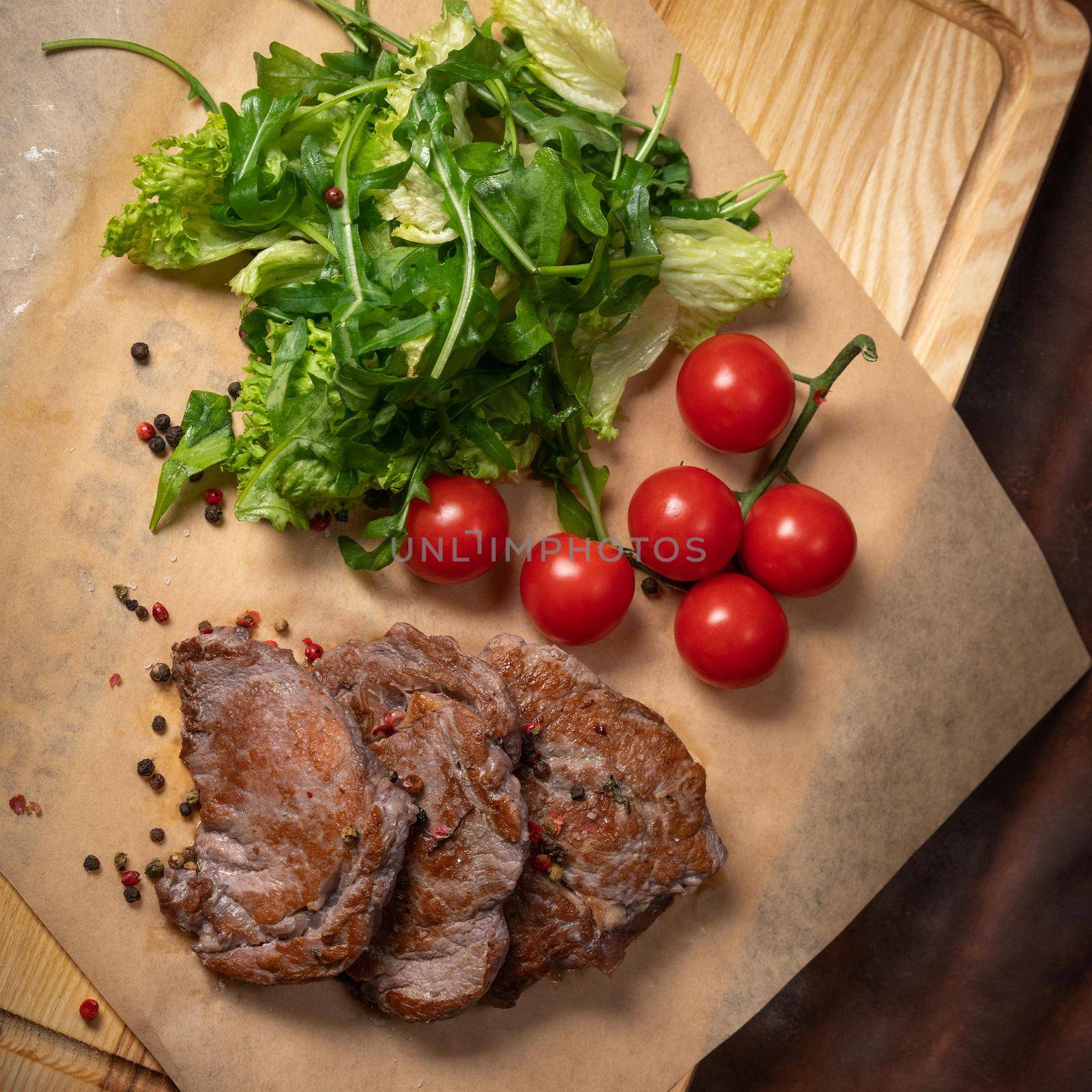 Grilled beef steak with fresh lettuce salad with arugula seeded pepper mixture and cherry tomatoes. Restaurant concept. Restaurant food. Grill concept. Square cropped by LipikStockMedia