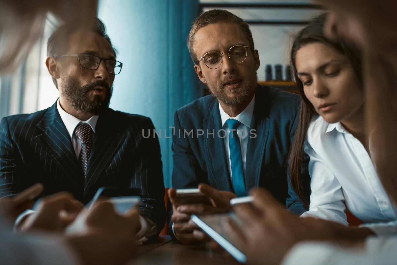 Young team of colleagues app developers testing the bugs of the new app while testing usability with different operation system gadgets. Freelancers updating software on gadgets by LipikStockMedia