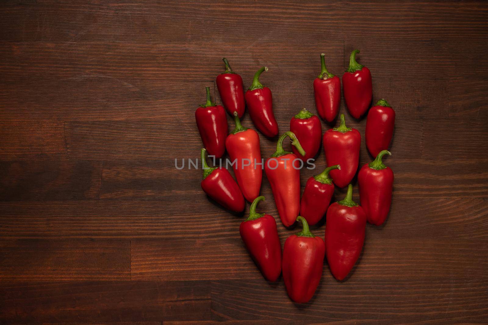 Fresh heart of chillies or peppers and capsicums or bell peppers. Sweet bell, paprika, cayenne, chilli, Hungarian wax pepper, isolated on wooden table background. Valentine day concept. Copy space.