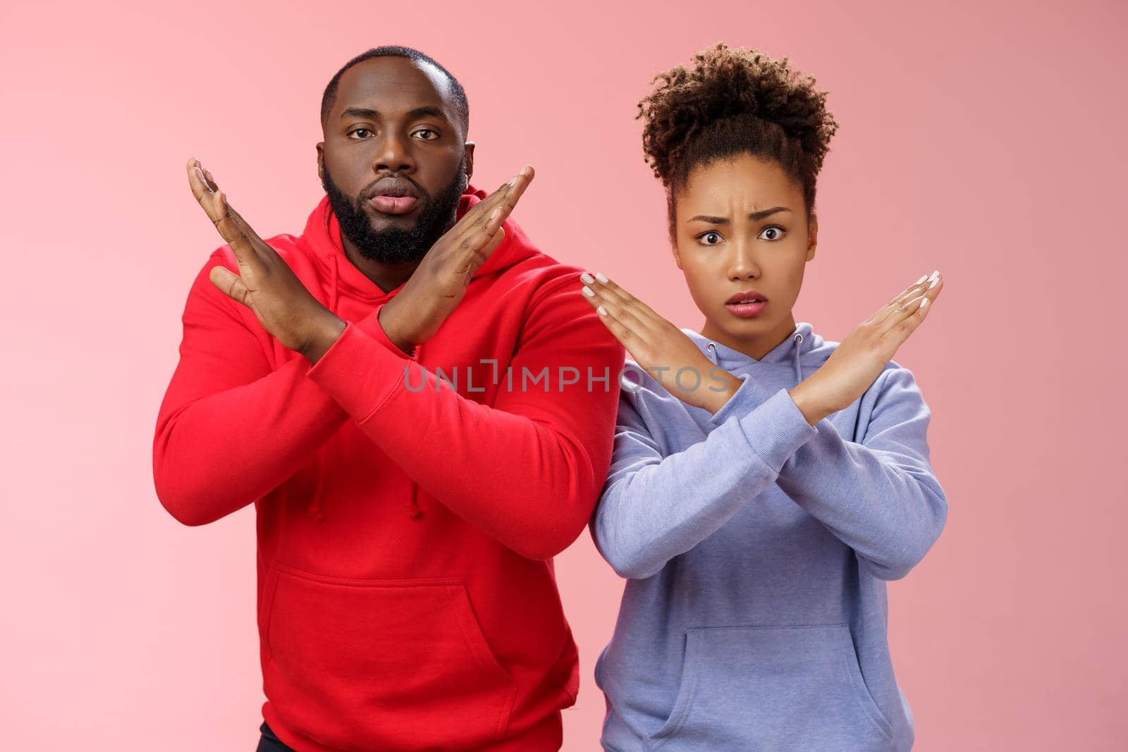 Nervous displeased two african-american man woman asking friend tell they absent not here show cross signs frowning disturbed worried begging not tell quit, stop standing pink background by Benzoix
