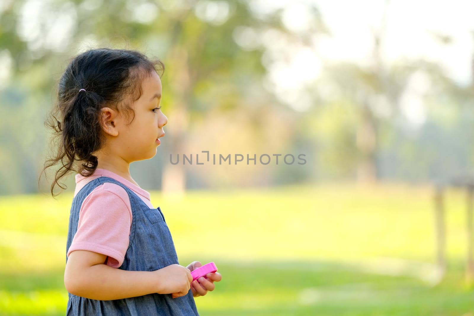 Close up on side of little girl enjoy with playing in the green garden with morning light and copy space.