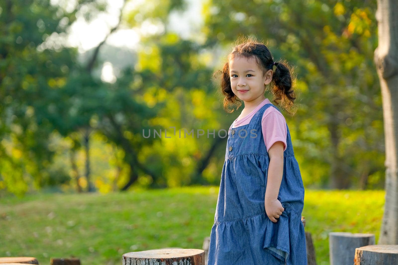 Young Asian little girl play alone in the garden with morning light.