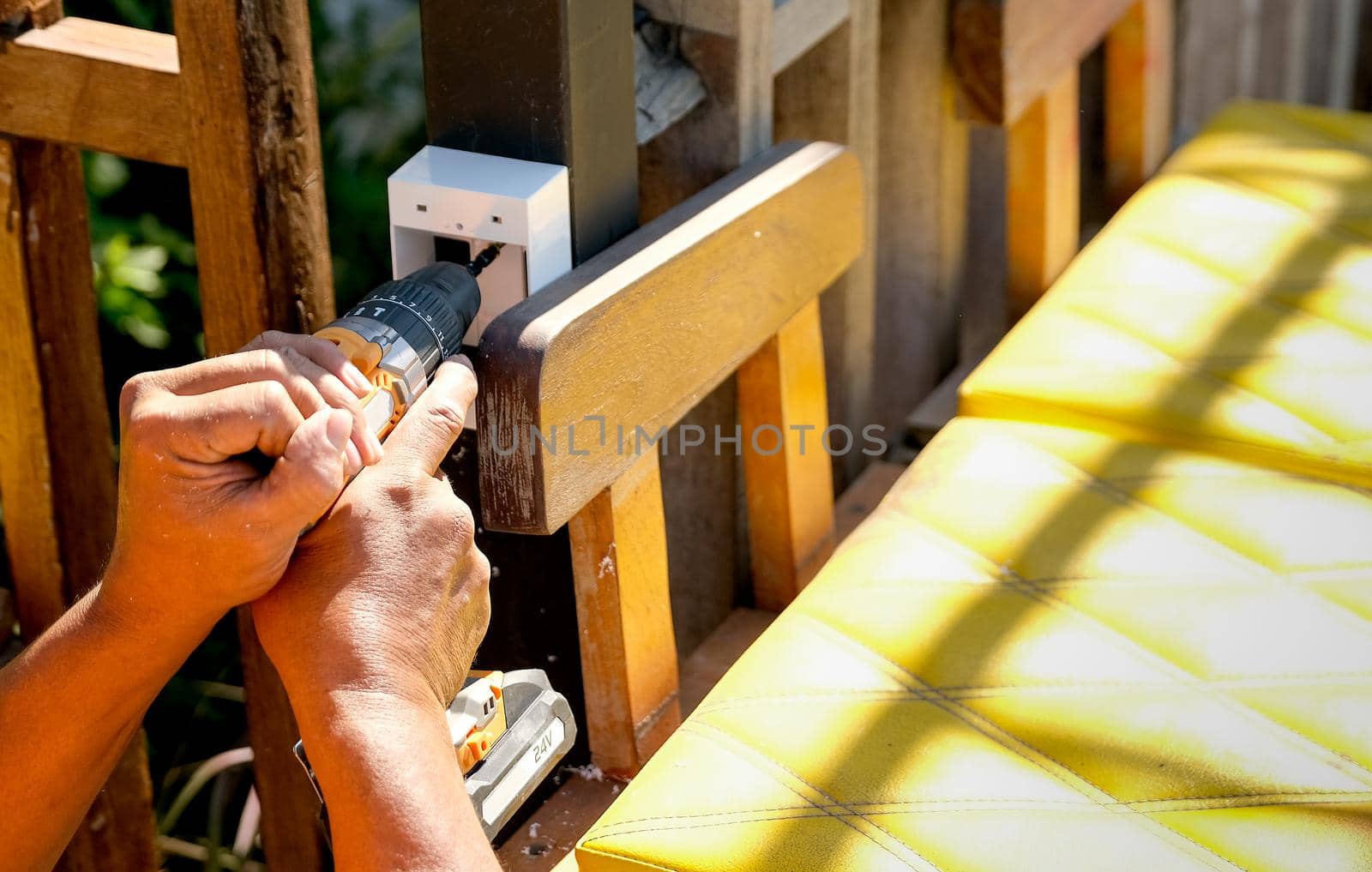 Hands with drill that working with electrical plug in the garden.