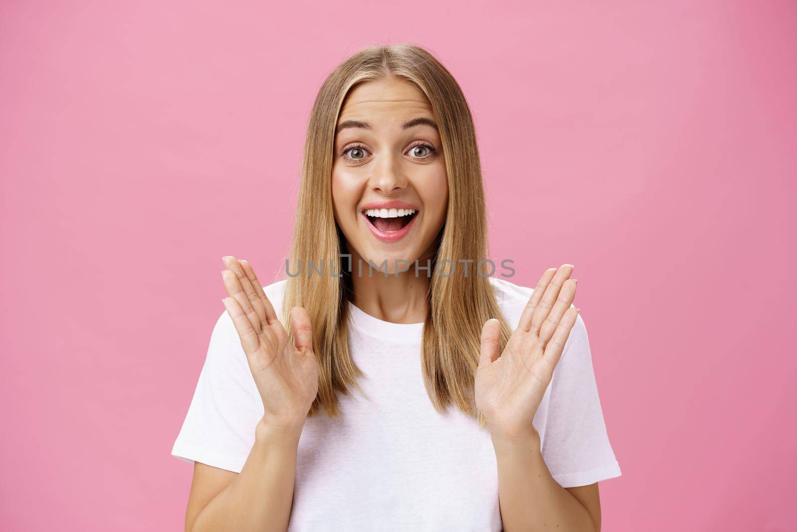 Woman learning awesome great news clasping hands in joy and excitement rejoicing feeling hapyp for friend smiling broadly and looking cheerful at camera with amused expression over pink background. Body language and emotions concept