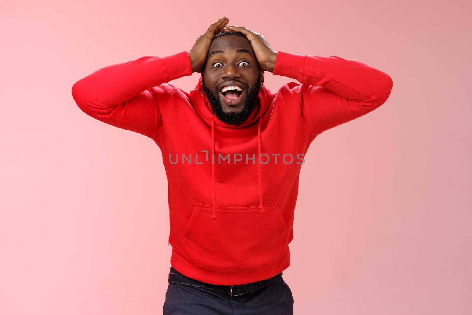 Guy receive very good surprising news cannot believe own happiness luck smiling broadly hold hands head impressed triumphing winning bet lottery, standing pink background joyful. Copy space