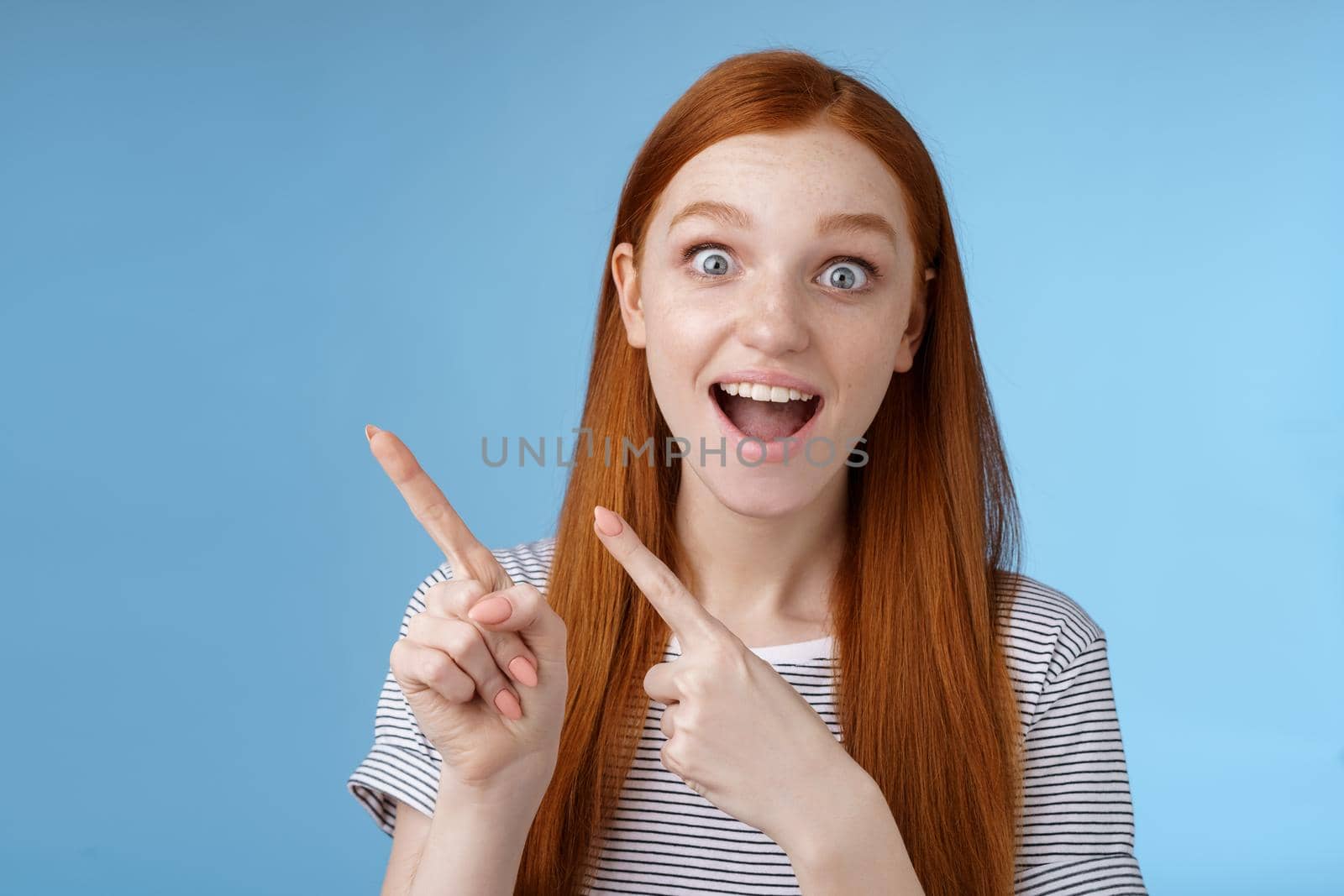 Lifestyle. Charismatic impressed surprised good-looking happy smiling cute redhead girl say wow grinning astonished wide eyes pointing upper left corner stunned thrilled speechless see awesome promo.