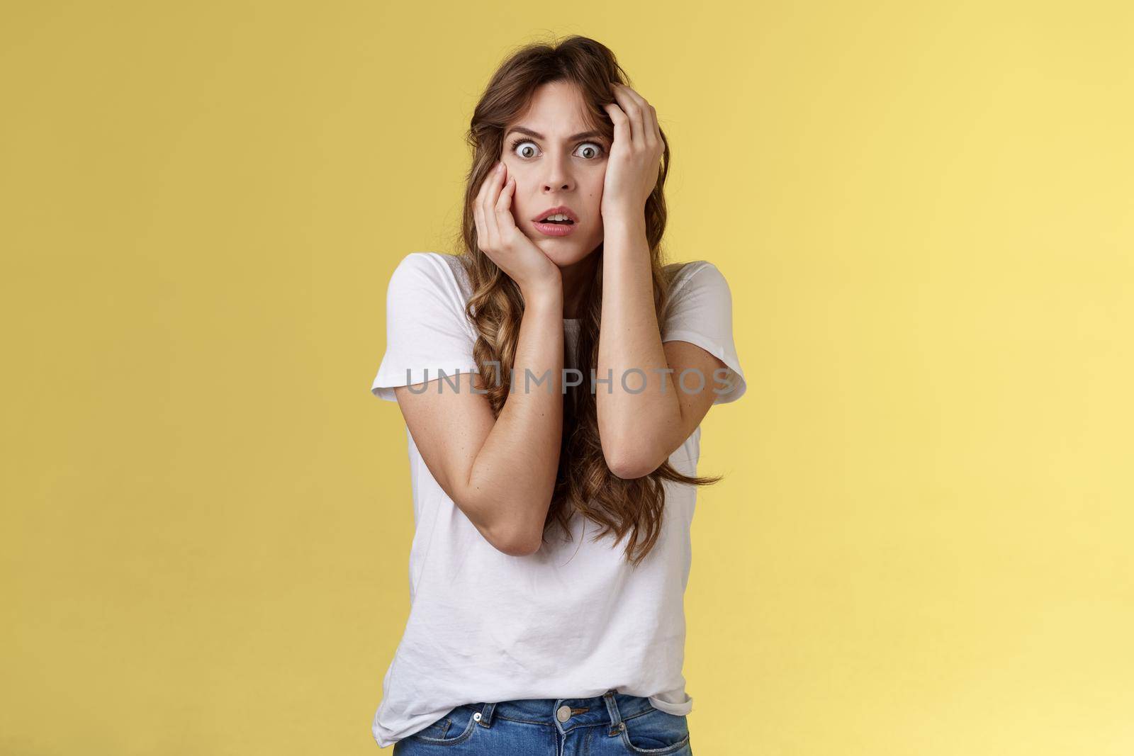 Oh my god someone save me. Scared stunned intense panicking young woman grab head stare camera frightened open mouth gasping shocked standing stupor yellow background timid insecure by Benzoix