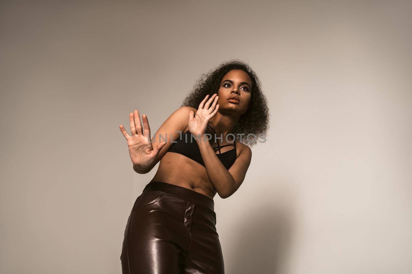 Scared with blocking hands young girl stands pinched, wearing leather pants and black top. Women violence and abused concept. trafficking Concept.
