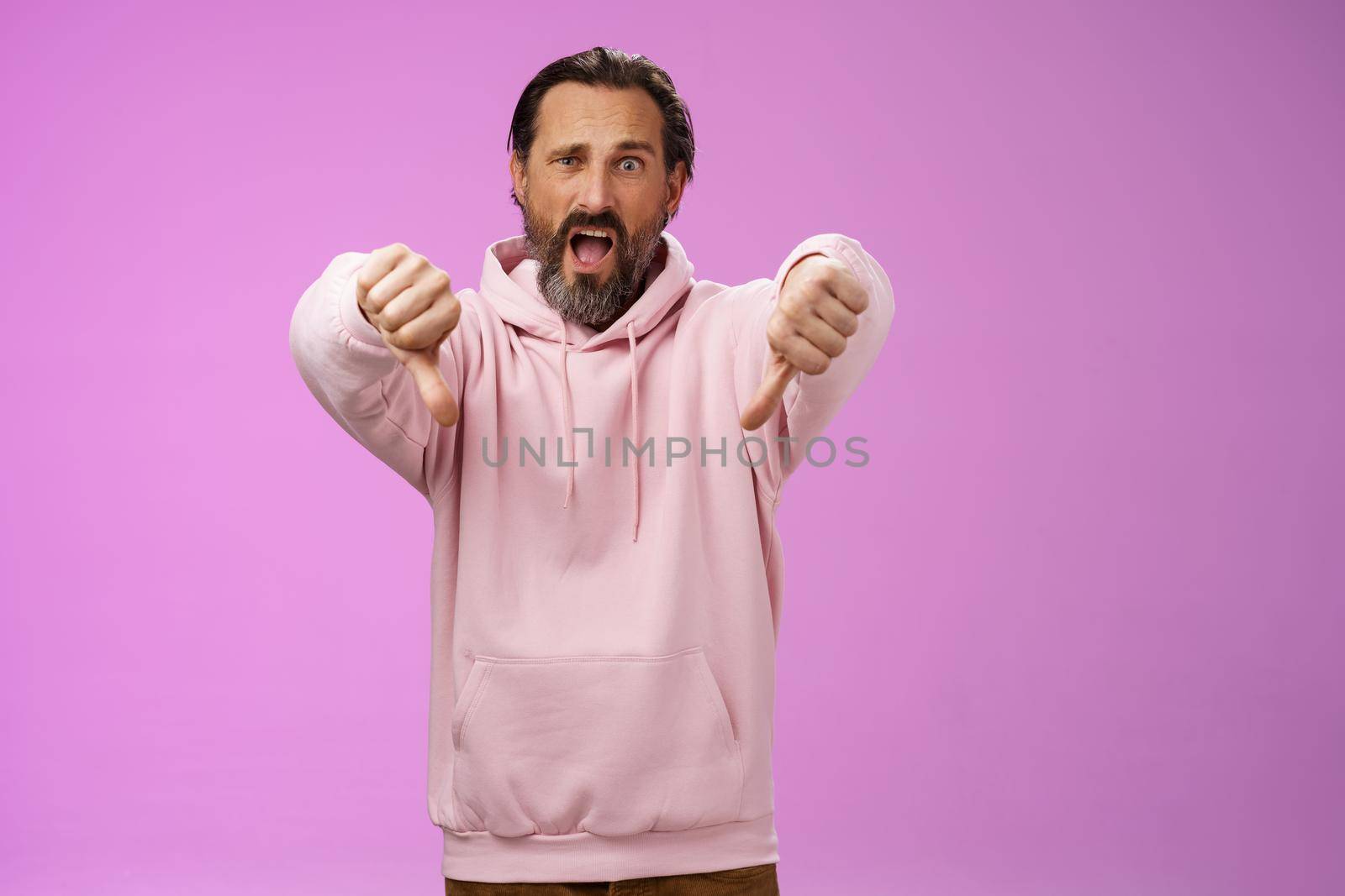 Extremely disappointed furious male customer swearing show thumbs down impulsive gesture yelling displeased pissed express dislike disgust look judgemental bothered, standing purple background by Benzoix