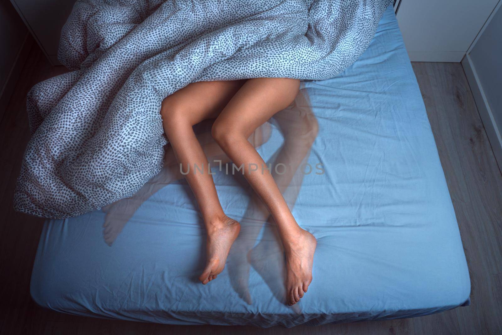 Woman sleeping in the bed and suffering from RLS or restless legs syndrome by DariaKulkova