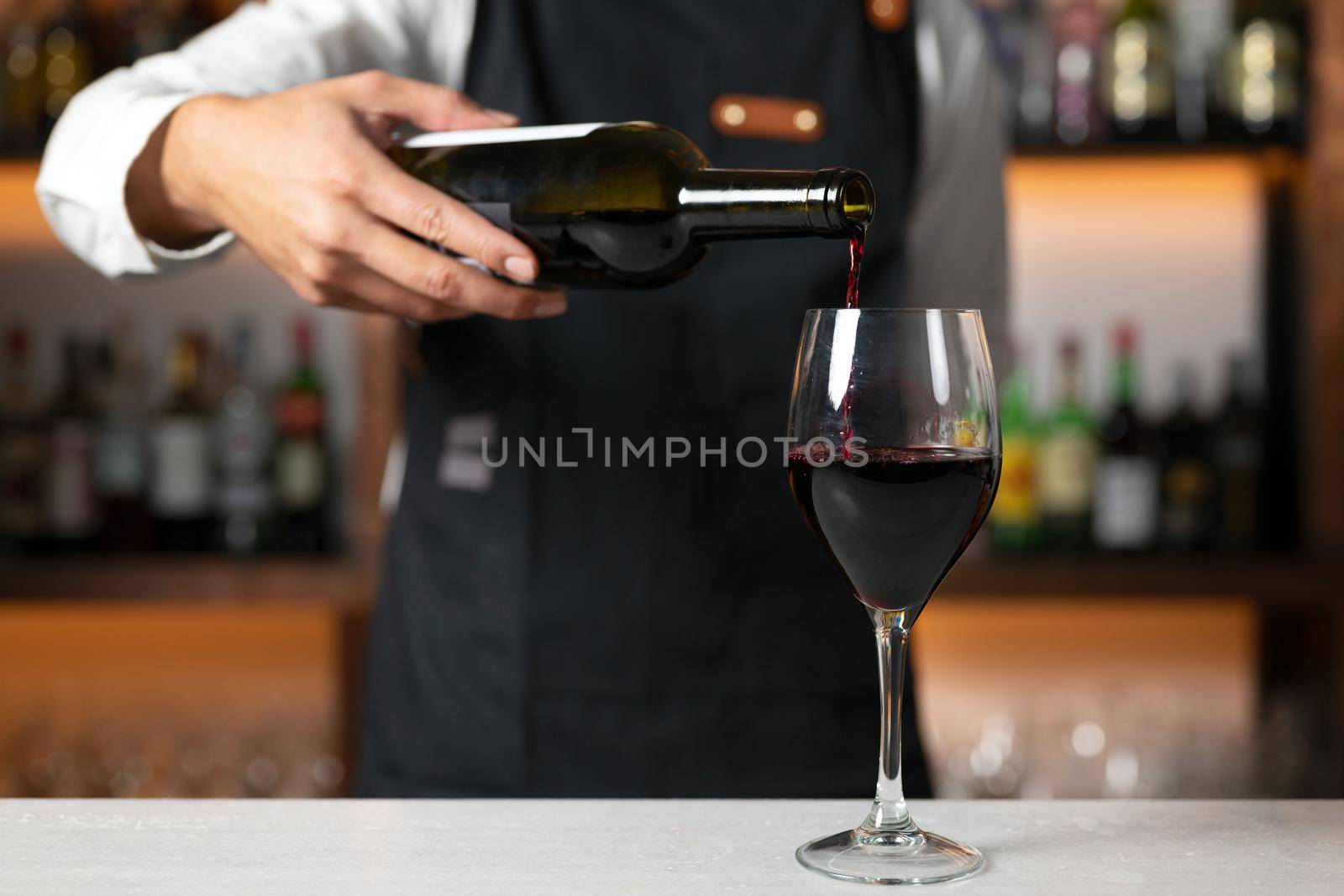 Unrecognizable Bartender serving red wine. High quality photography by HERRAEZ