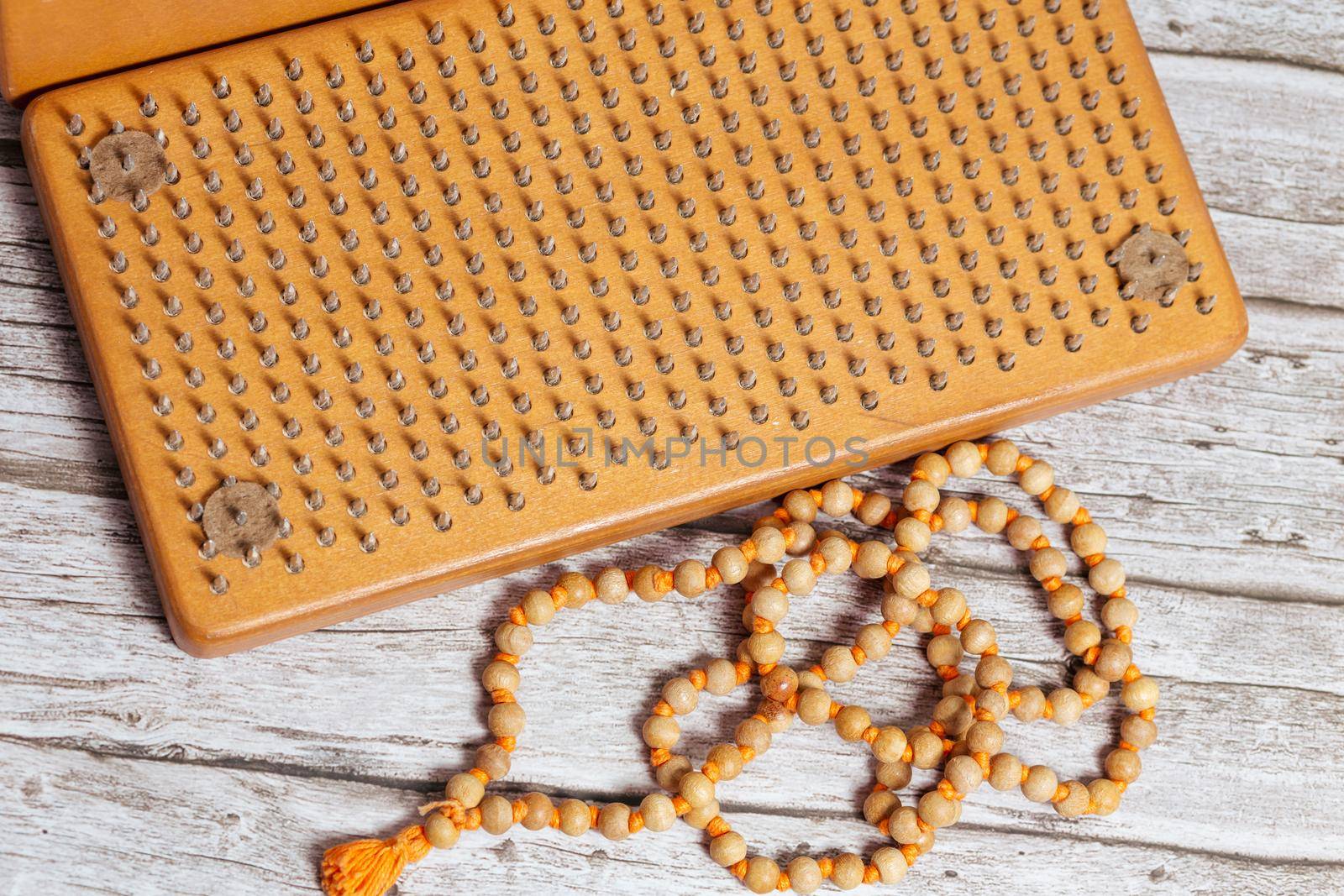 Tibetan Buddhist rosary, called mala or japamala. Brown Sadhu wooden boards with nails for yoga and spiritual practices on the grey background. The concept of meditation, standing on nails, therapy.