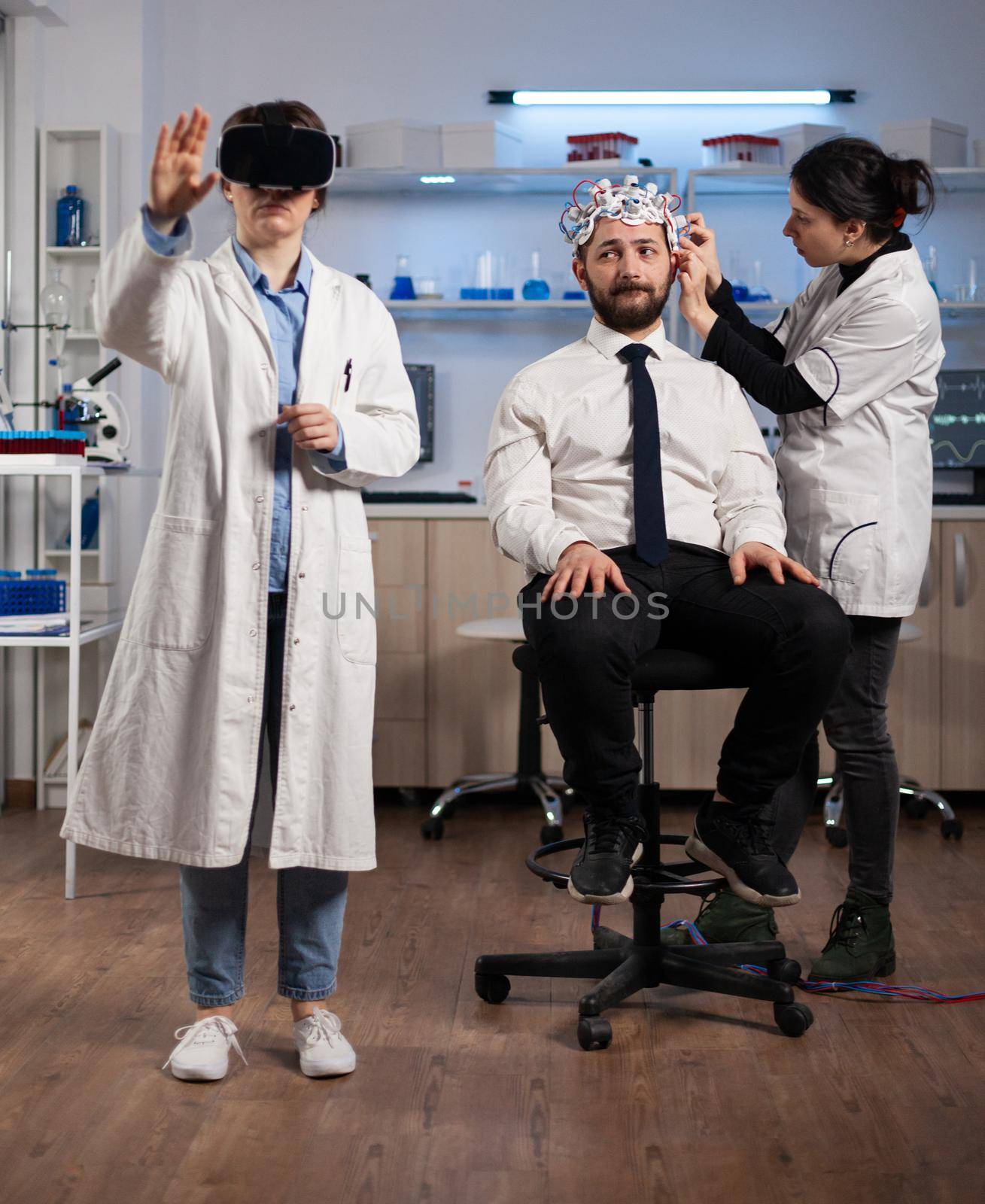 Researcher woman wearing virtual reality headset during neurology experiment in medical laboratory. Neurologist doctor adujusting eeg scanner monitoring brain activity analyzing nervous system