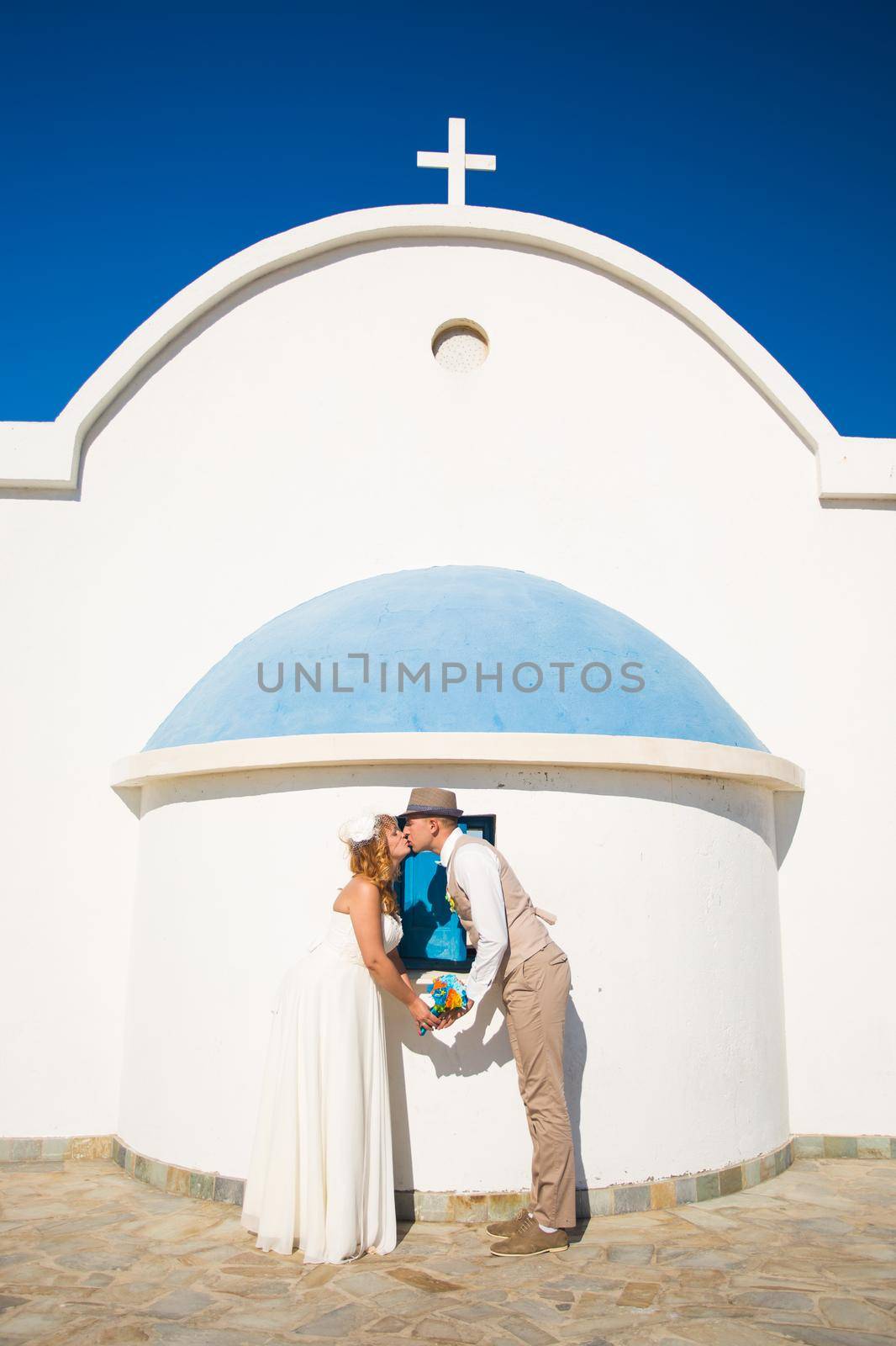 Funny beautiful bride and groom with a church on the background by Satura86