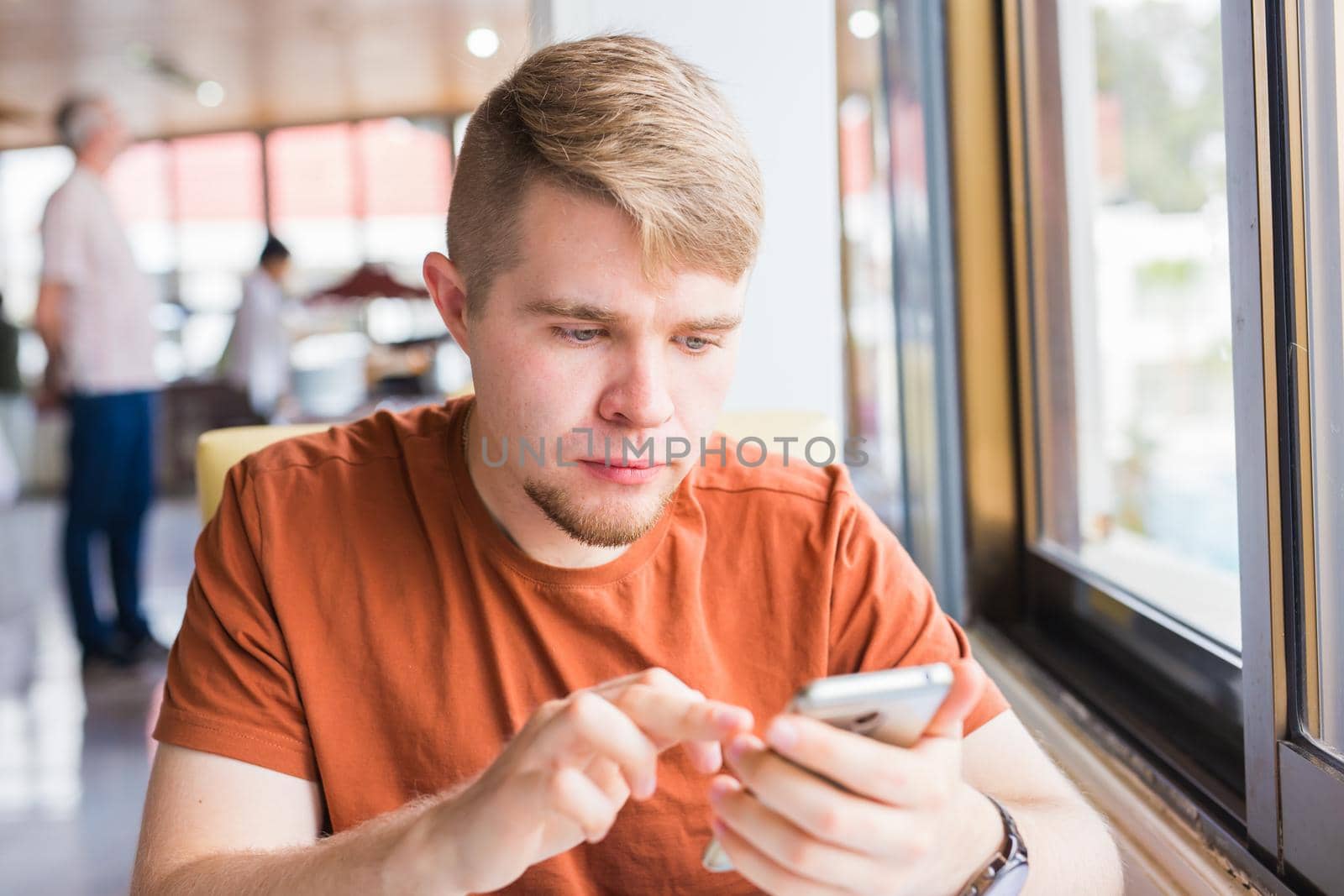 leisure, technology, communication and people concept - close up of man with smartphone texting message in city cafe.