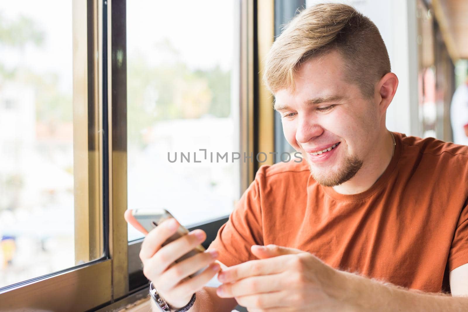 leisure, technology, communication and people concept - close up of man with smartphone texting message in city cafe.