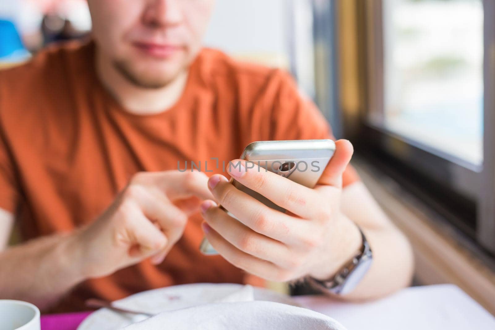 leisure, technology, communication and people concept - close up of man with smartphone texting message in city cafe.