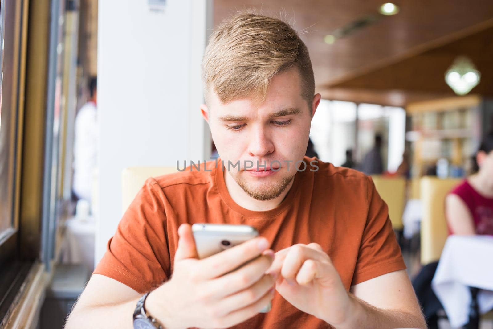 leisure, technology, communication and people concept - close up of man with smartphone texting message in city cafe.