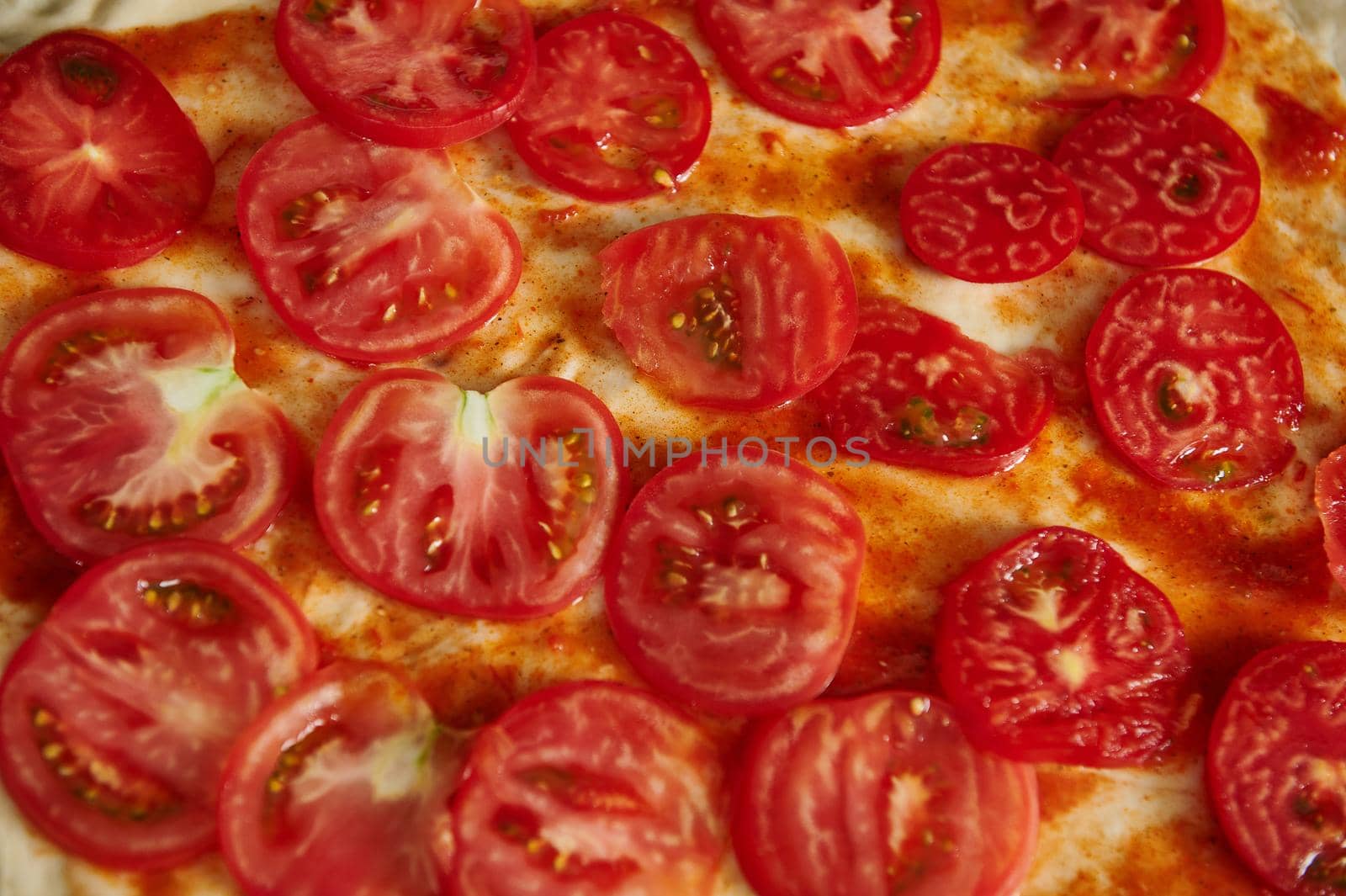 Close-up of tomatoes slices on pizza dough. Flat lay, top view, pattern by artgf