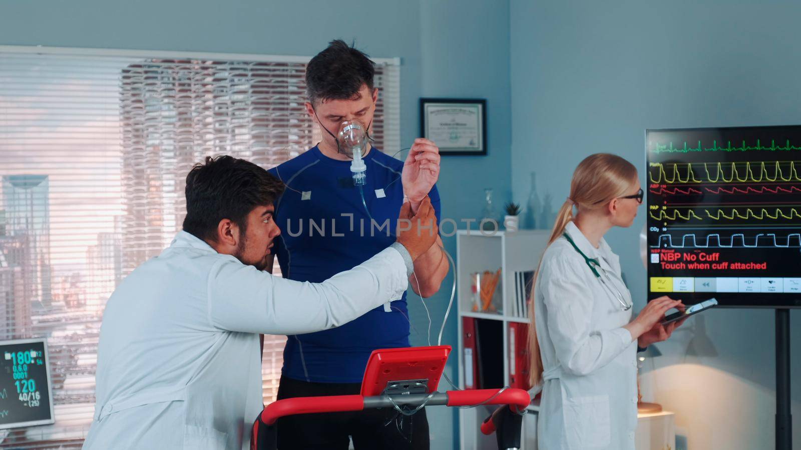 Doctor preparing sportsman in oxygen mask for cardio respiratory test by checking electrodees and mask connection in scientific sport laboratory.