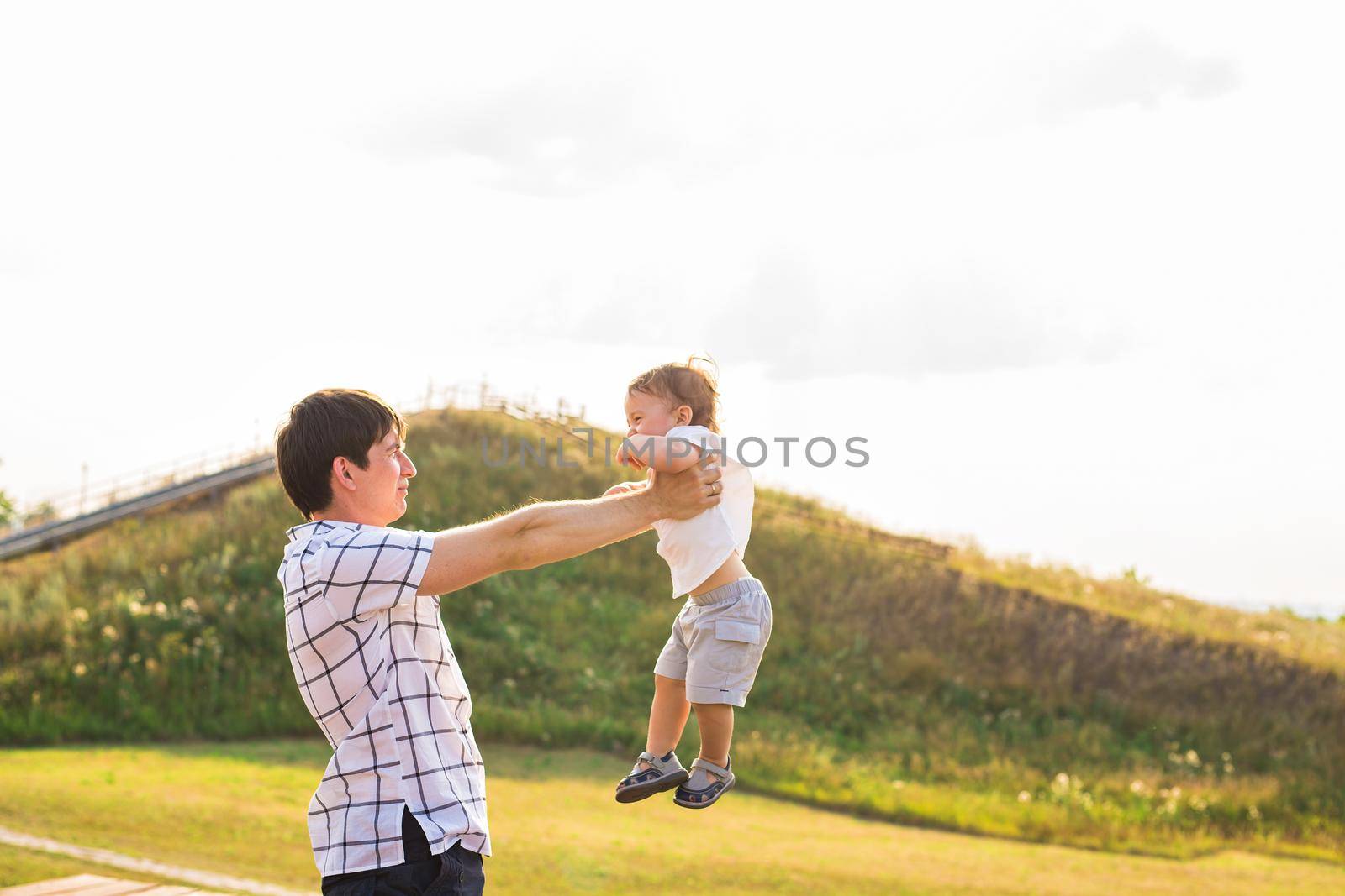 Happy child, dad and son having fun, holding on hands on a sunlight sunset background. Family, travel, vacation, childhood, father's day - concept by Satura86
