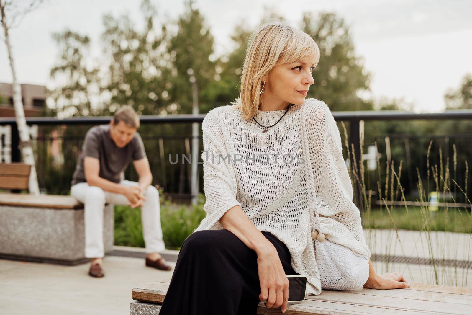 Mature couple in a bad mental condition after a quarrel outdoors. Adult couple man and woman trying to overcome anxiety and disorder after a break-up scene.