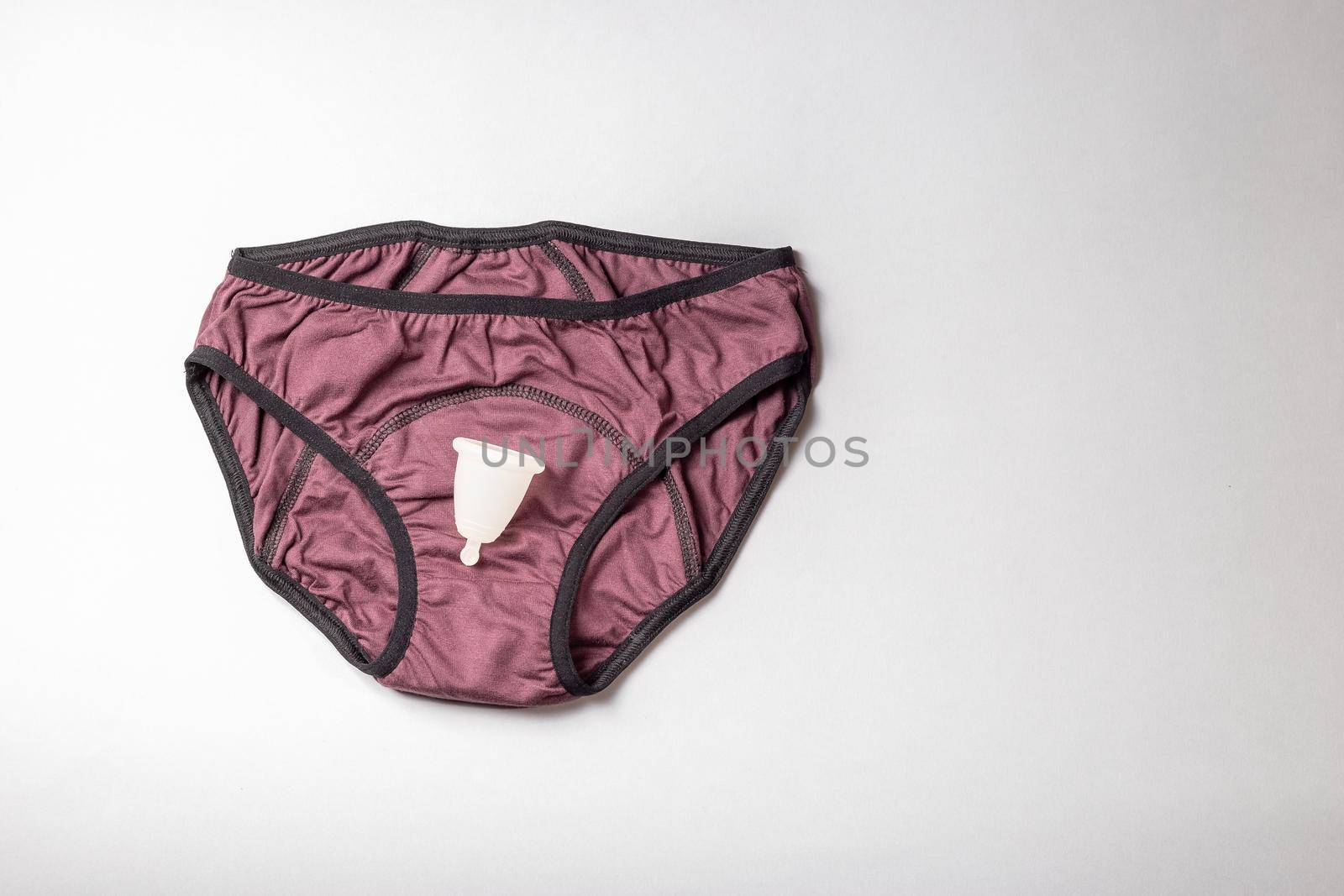 Reusable period products, menstruation underwear panties and menstrual cup. Top view on gray background.