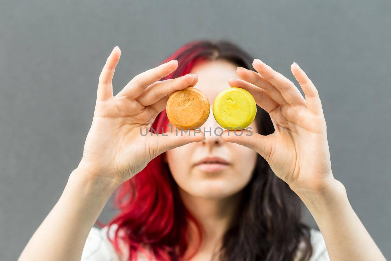 Woman holding organic soap or solid shampoo with no packaging over gray background. Healthy lifestyle, beauty, skin care, Zero waste concept.
