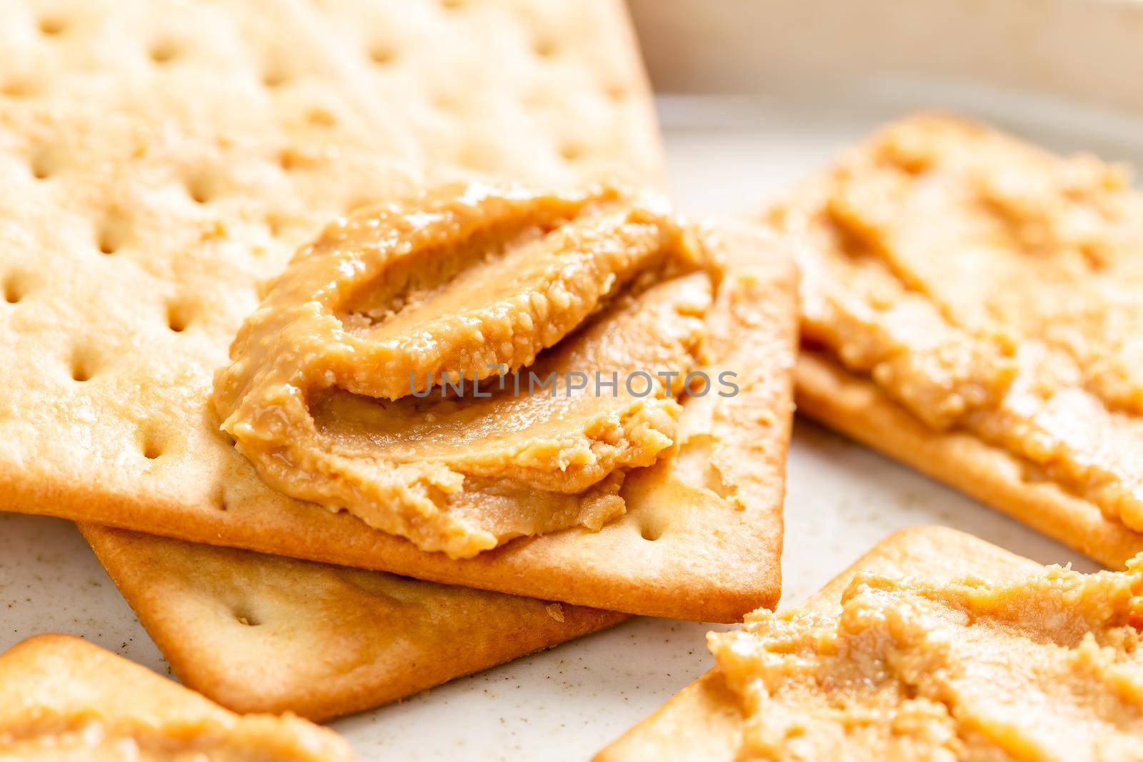 Crunchy peanut butter spread on soda crackers close up