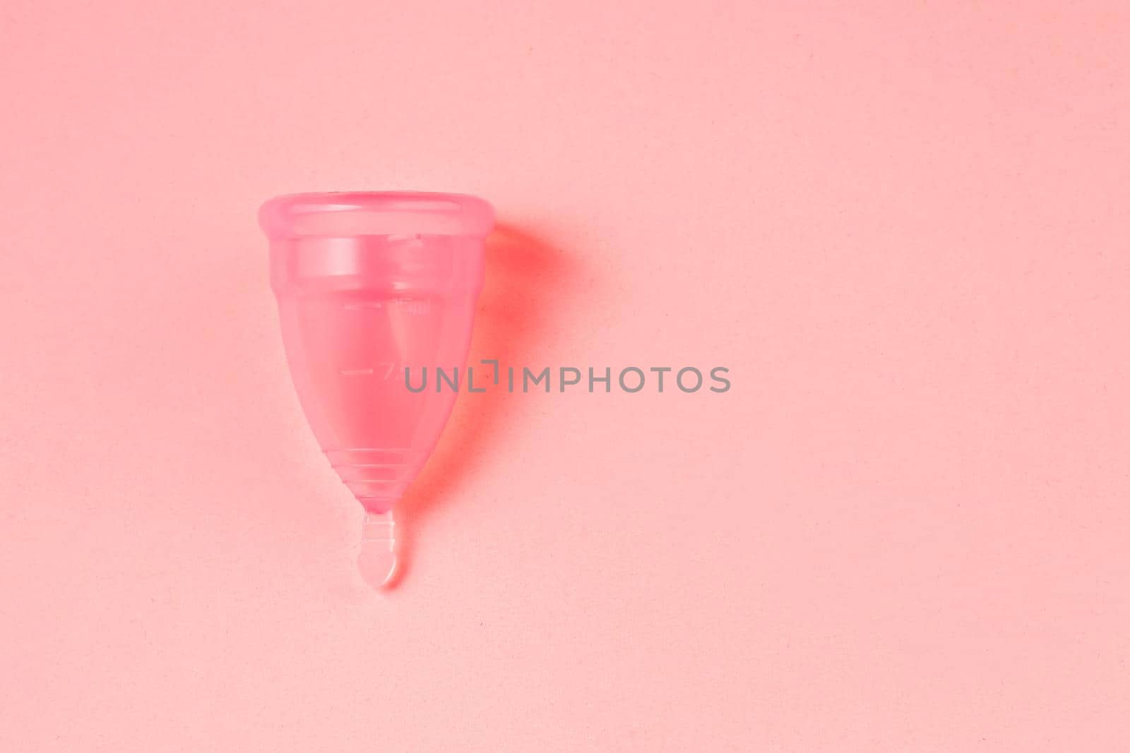 Pink Menstrual cup on bright pink background. Alternative eco friendly feminine hygiene product. Copy space.