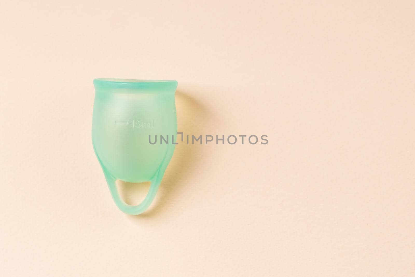 Blue silicone menstrual cup on beige pastel background by Syvanych