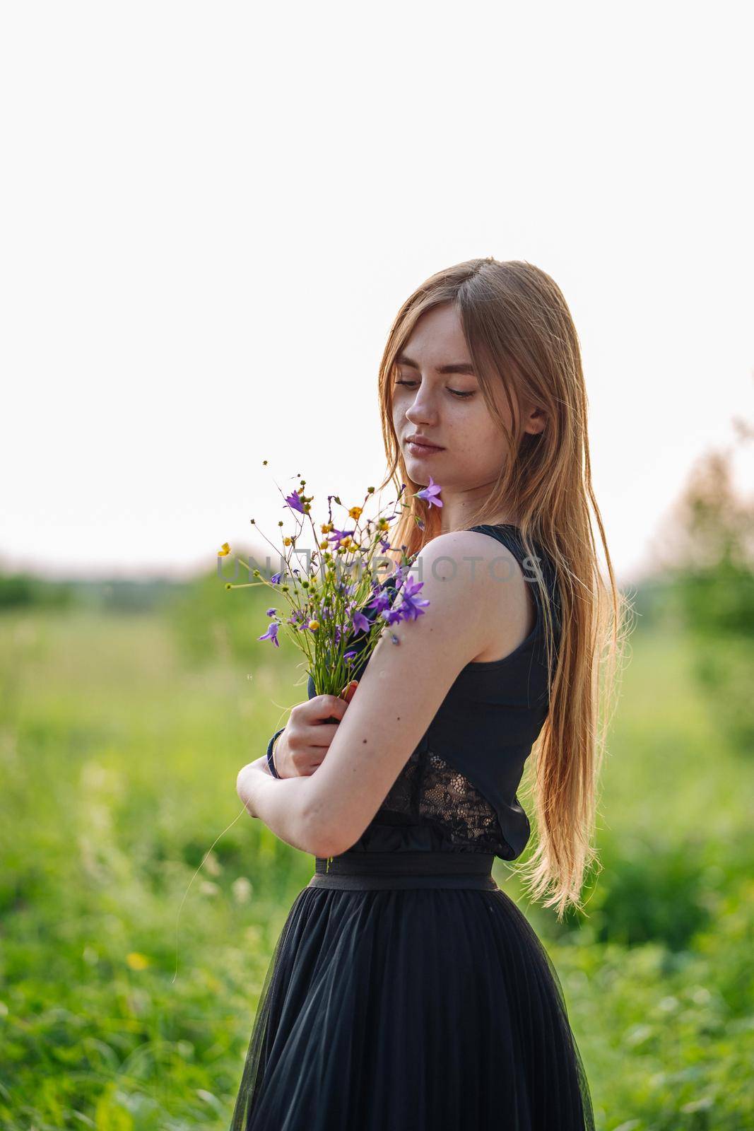 Portrait of a Russian girl with a bouquet of wild flowers in the evening at the village