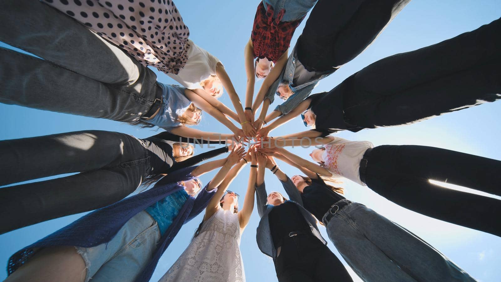 Eleven cheerful girlfriends make their hands together on a sunny day