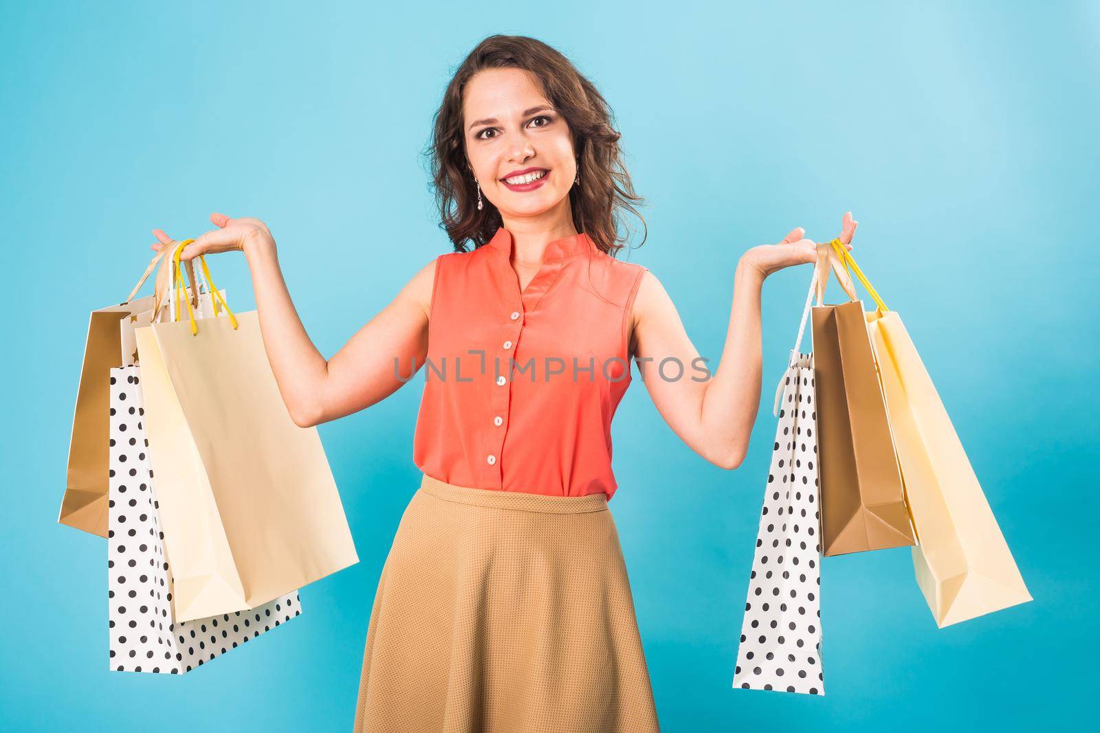 Young woman with shopping bags over blue background.