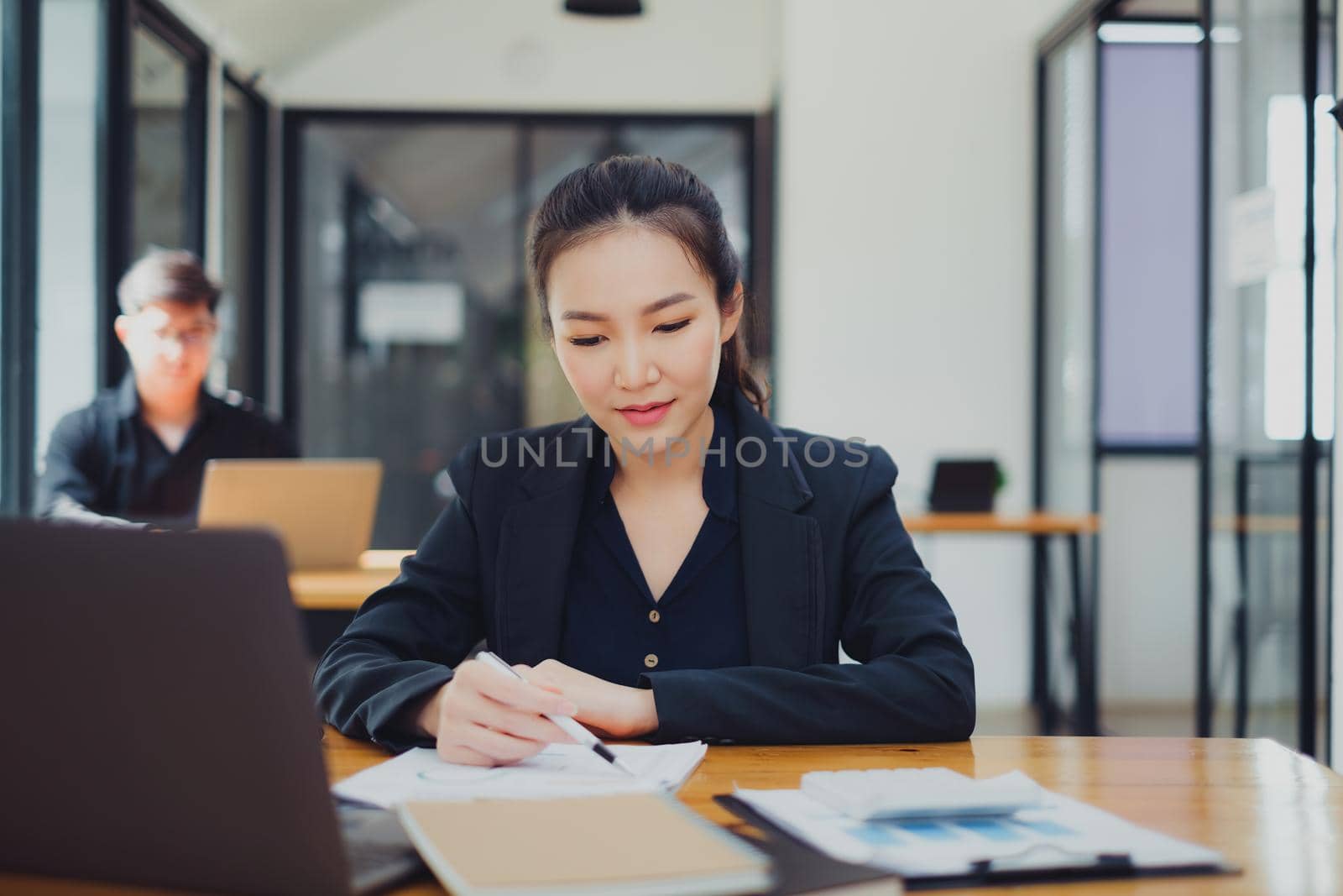 Business woman working to analyze technical price graph and indicator at office with businessman working on background. account or saving money or insurance concept