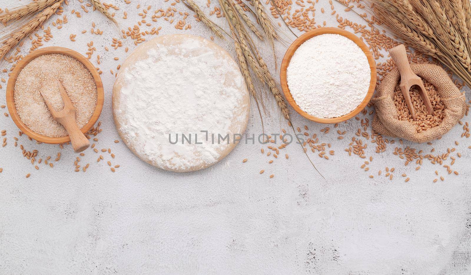 The ingredients for homemade pizza dough with wheat ears ,wheat flour and wheat grains set up on white concrete background. by kerdkanno