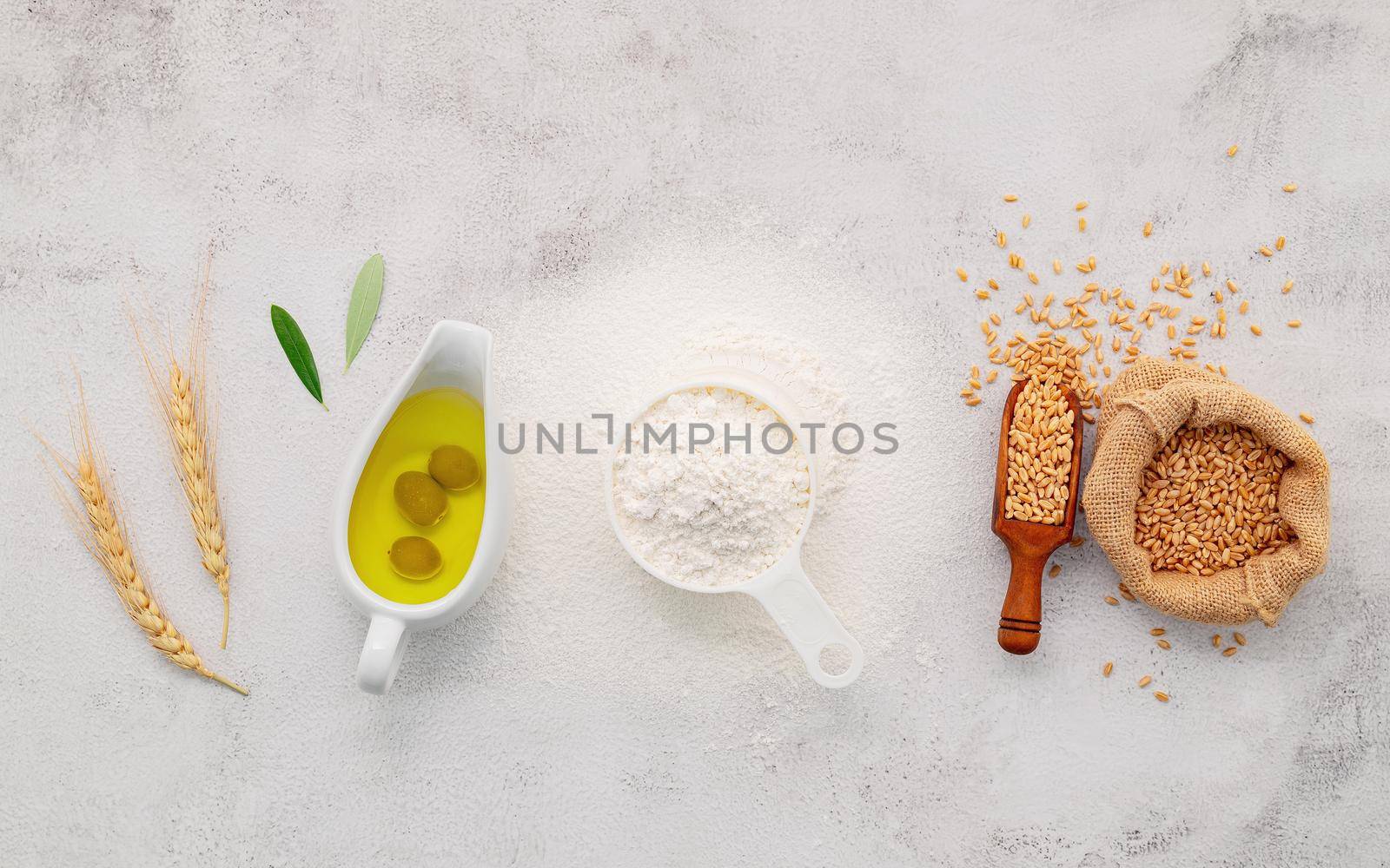 The ingredients for homemade pizza dough with wheat ears ,wheat flour and olive oil set up on white concrete background. top view and copy space. by kerdkanno