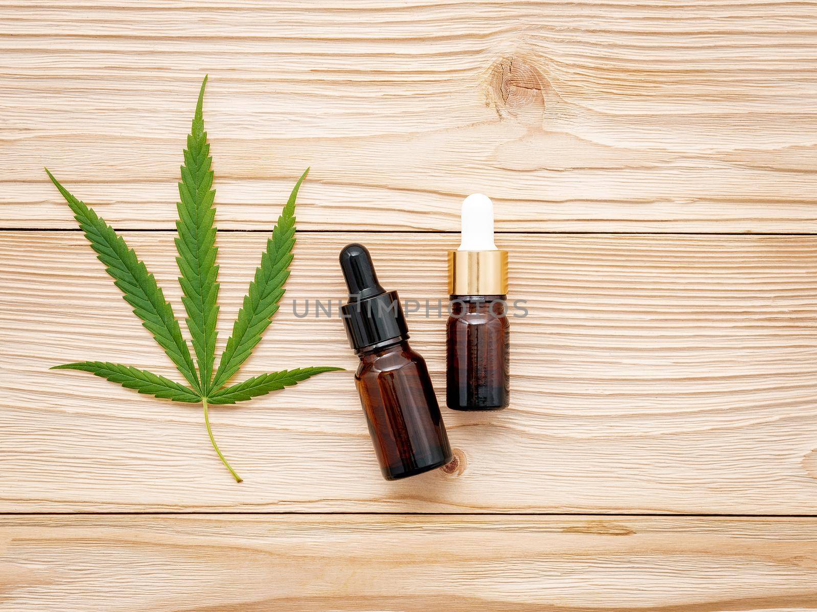Glass bottle of cannabis oil and hemp leaves set up  on wooden background.
