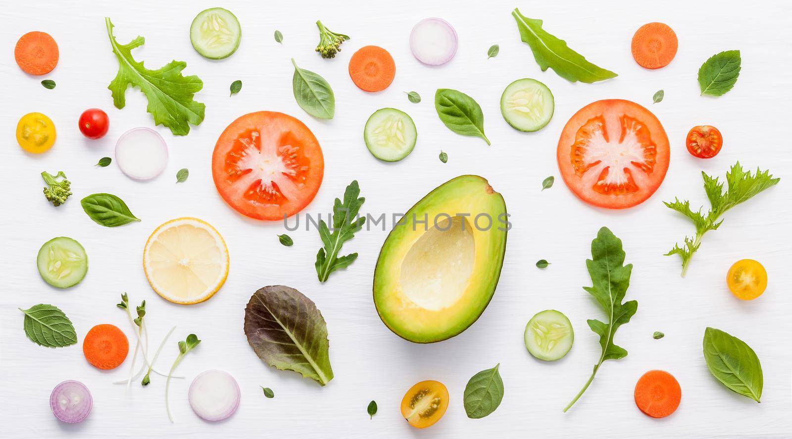 Food pattern with raw ingredients of salad, lettuce leaves, cucumbers, tomatoes, carrots, broccoli, basil ,onion and lemon flat lay on white wooden background. by kerdkanno