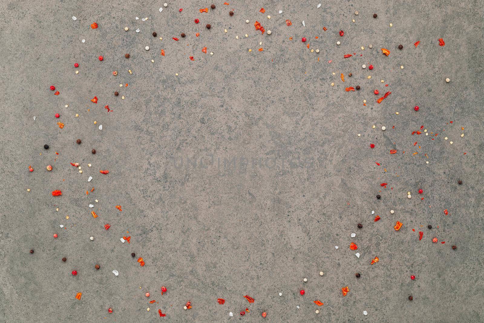 Top view of dark concrete background with peppercorn and chilli flakes.
